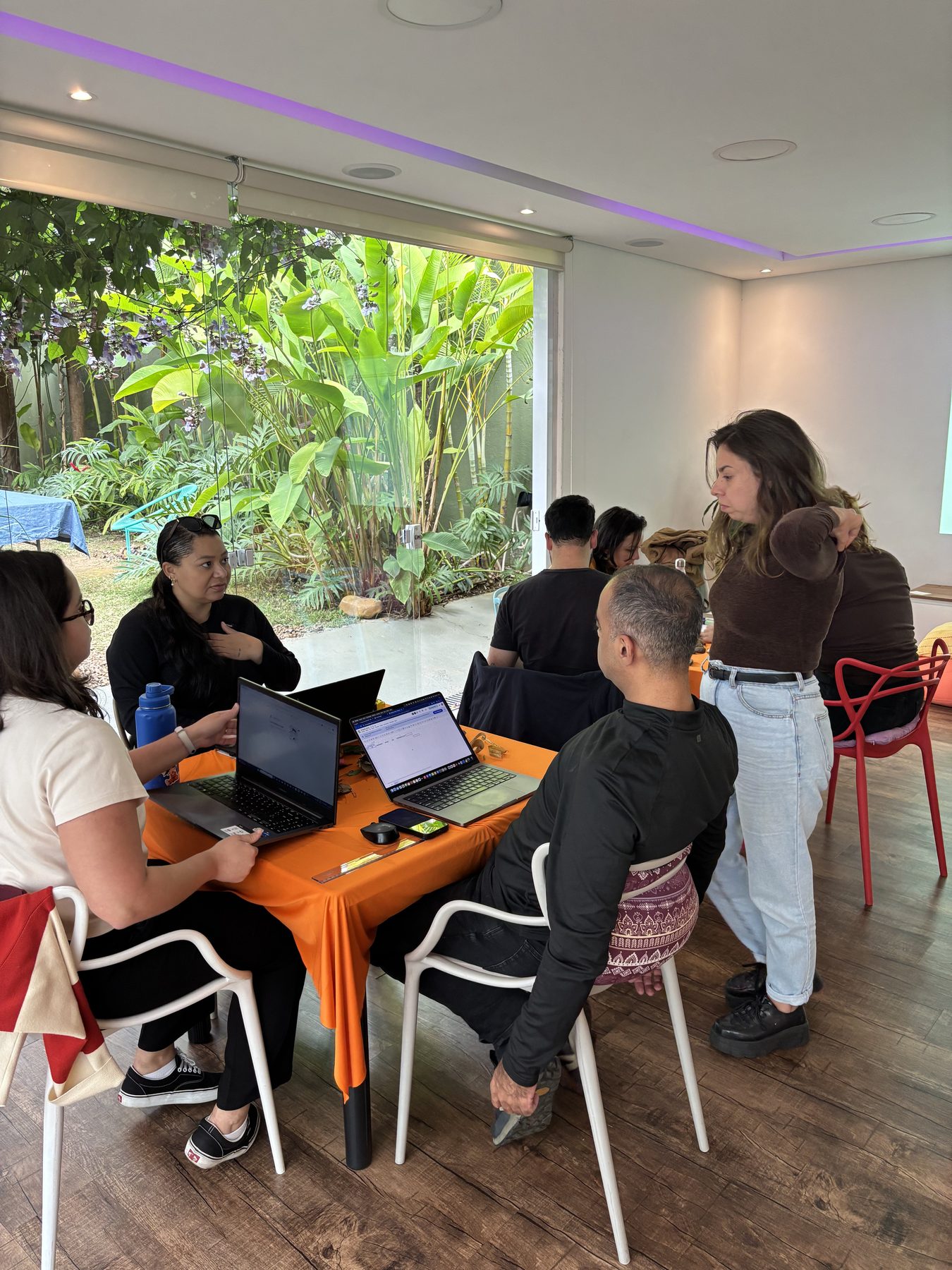 Participantes conversam em grupo durante uma atividade em espaço cercado de plantas