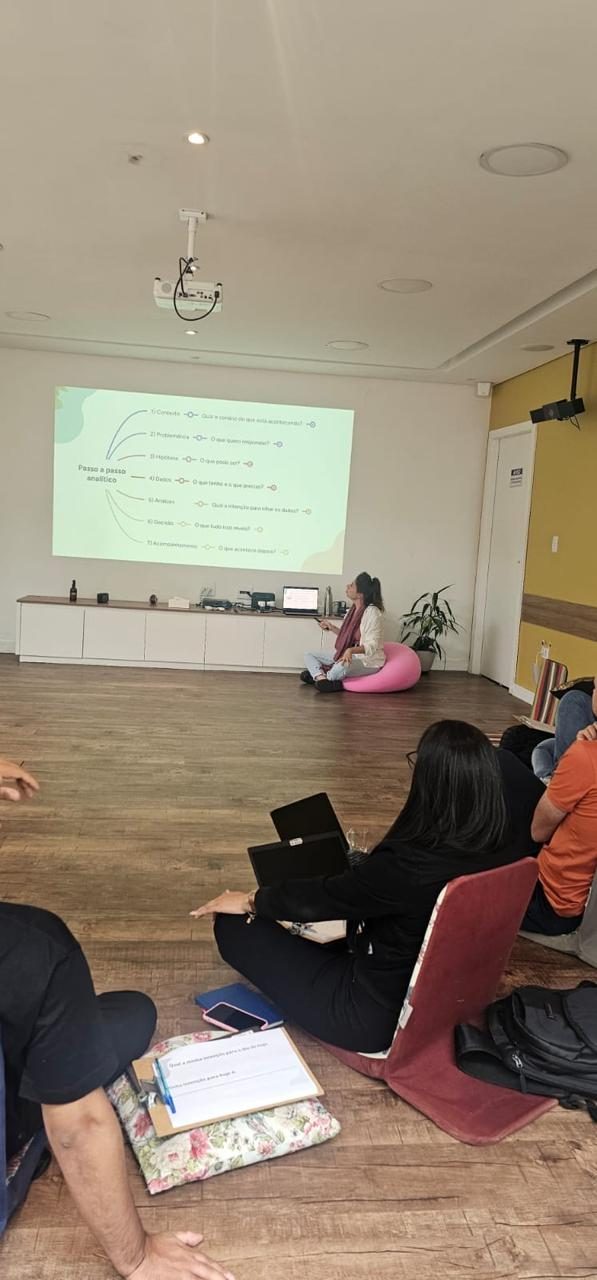 Participantes acompanham uma apresentação em uma sala de atividades